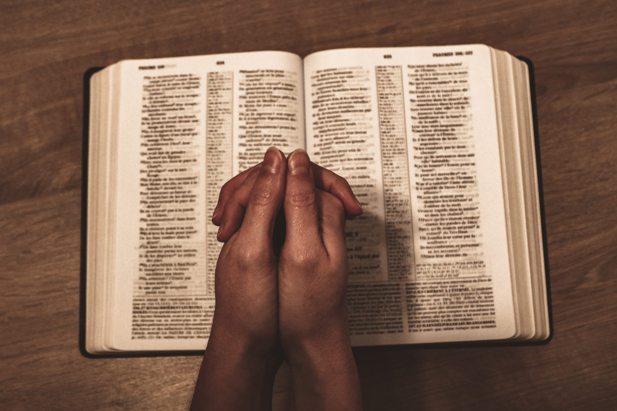 hands praying over bible