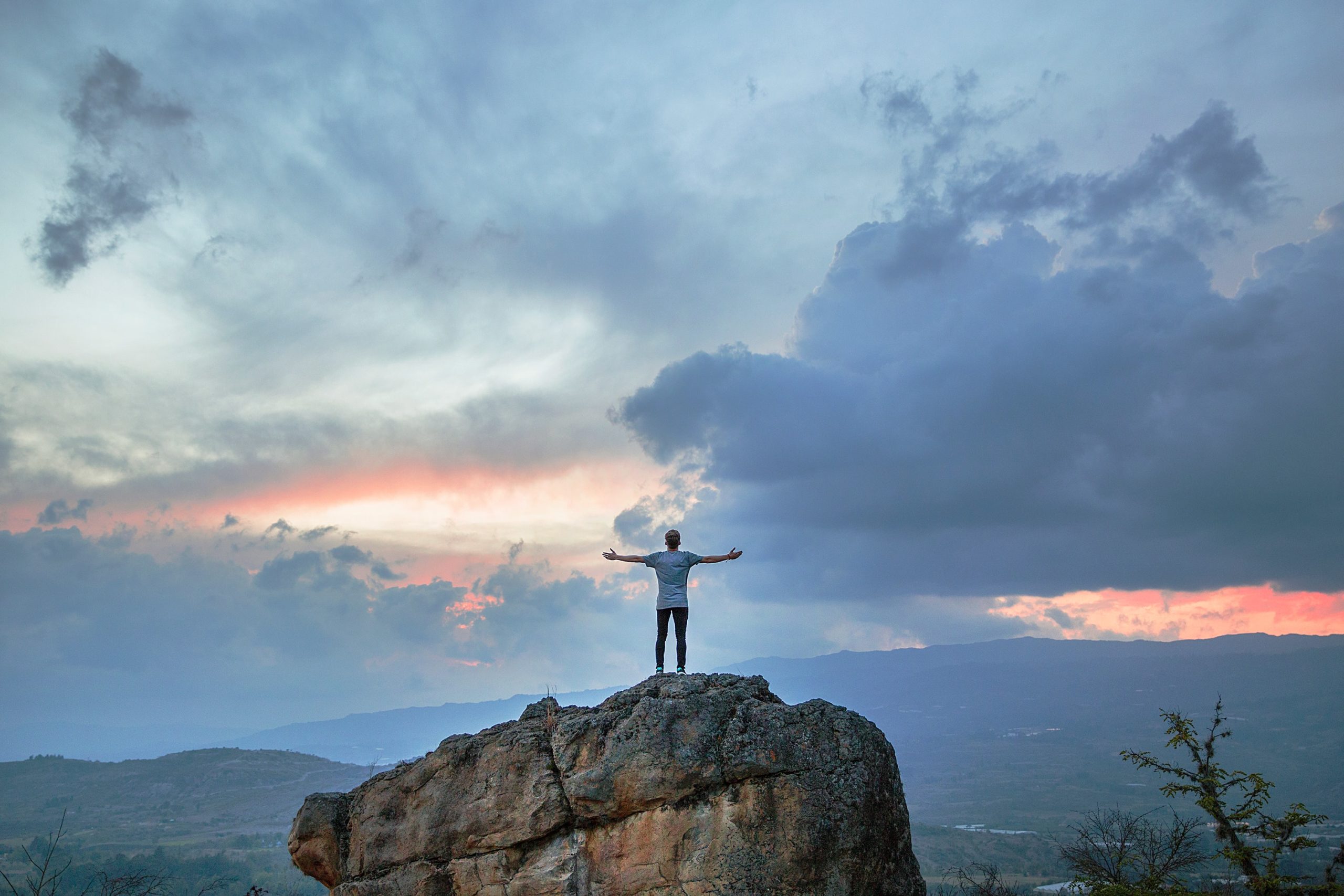 Man raising arms in thanks amid scenery