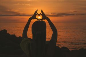 heart made of hands against sunset
